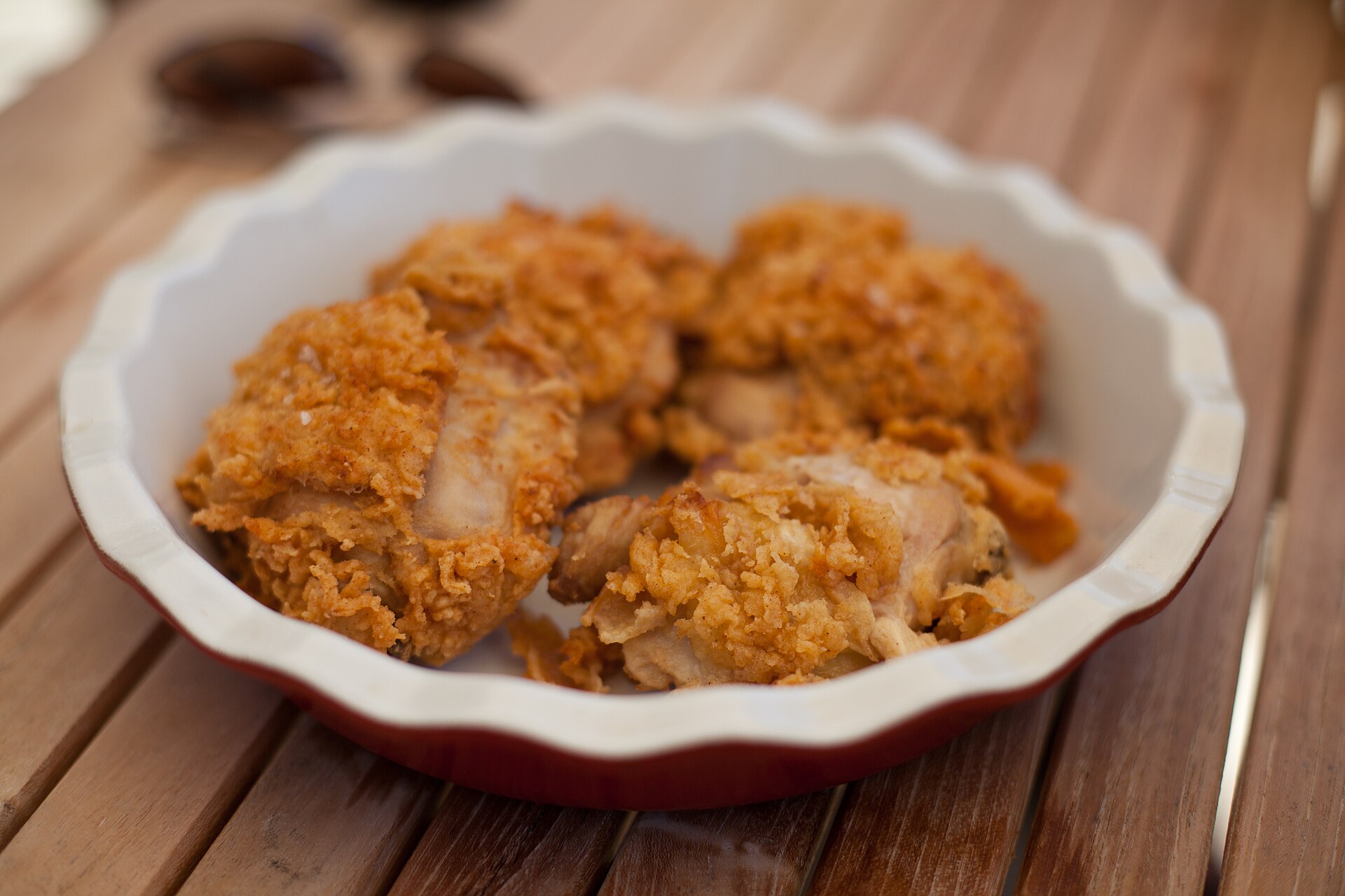 Fried chicken thighs in a fluted dish, cut open to show juicy meat